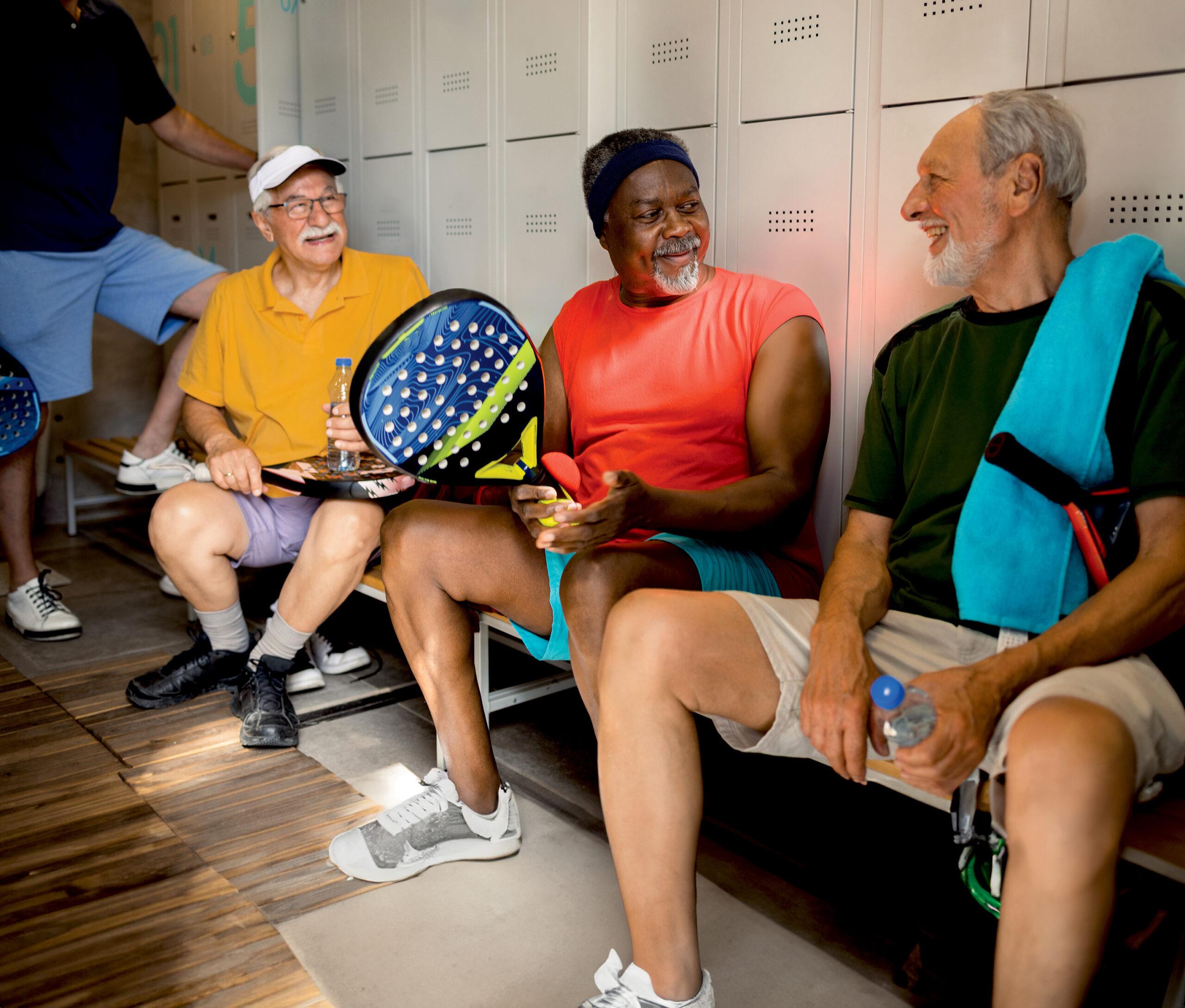 A group of friends talk and laugh in the locker room after a game of Paddle Tennis.