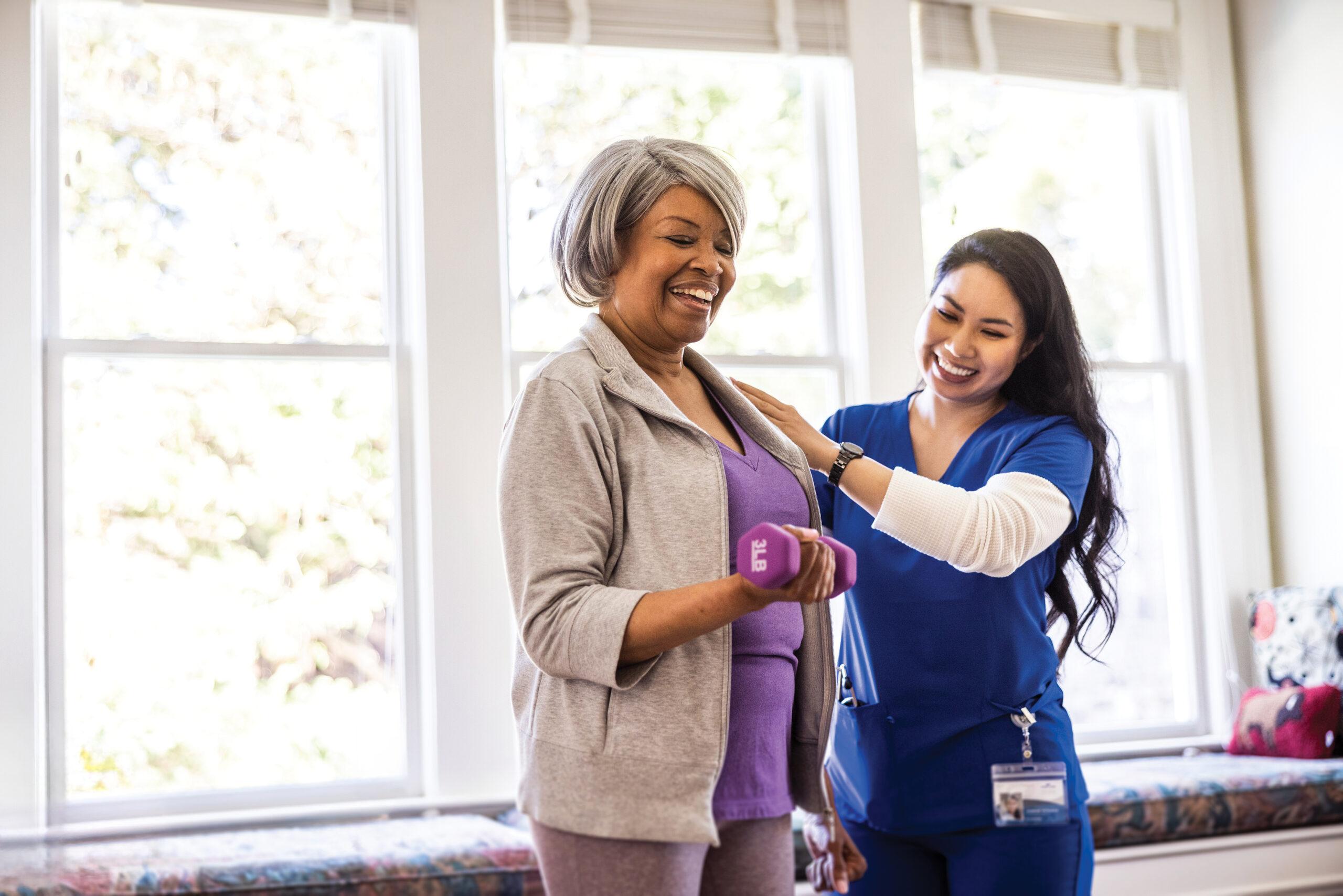 At home nurse helping senior woman with physical therapy at home.