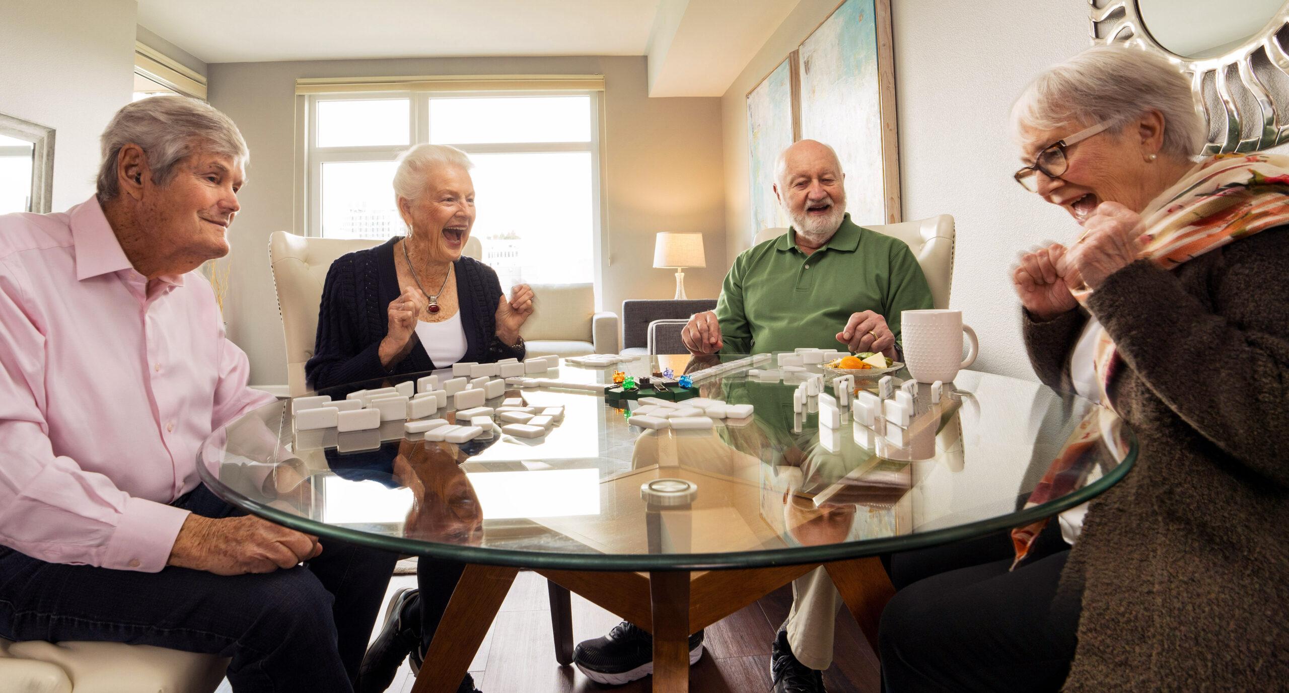 Four friends laugh and smile while playing a tabletop game.