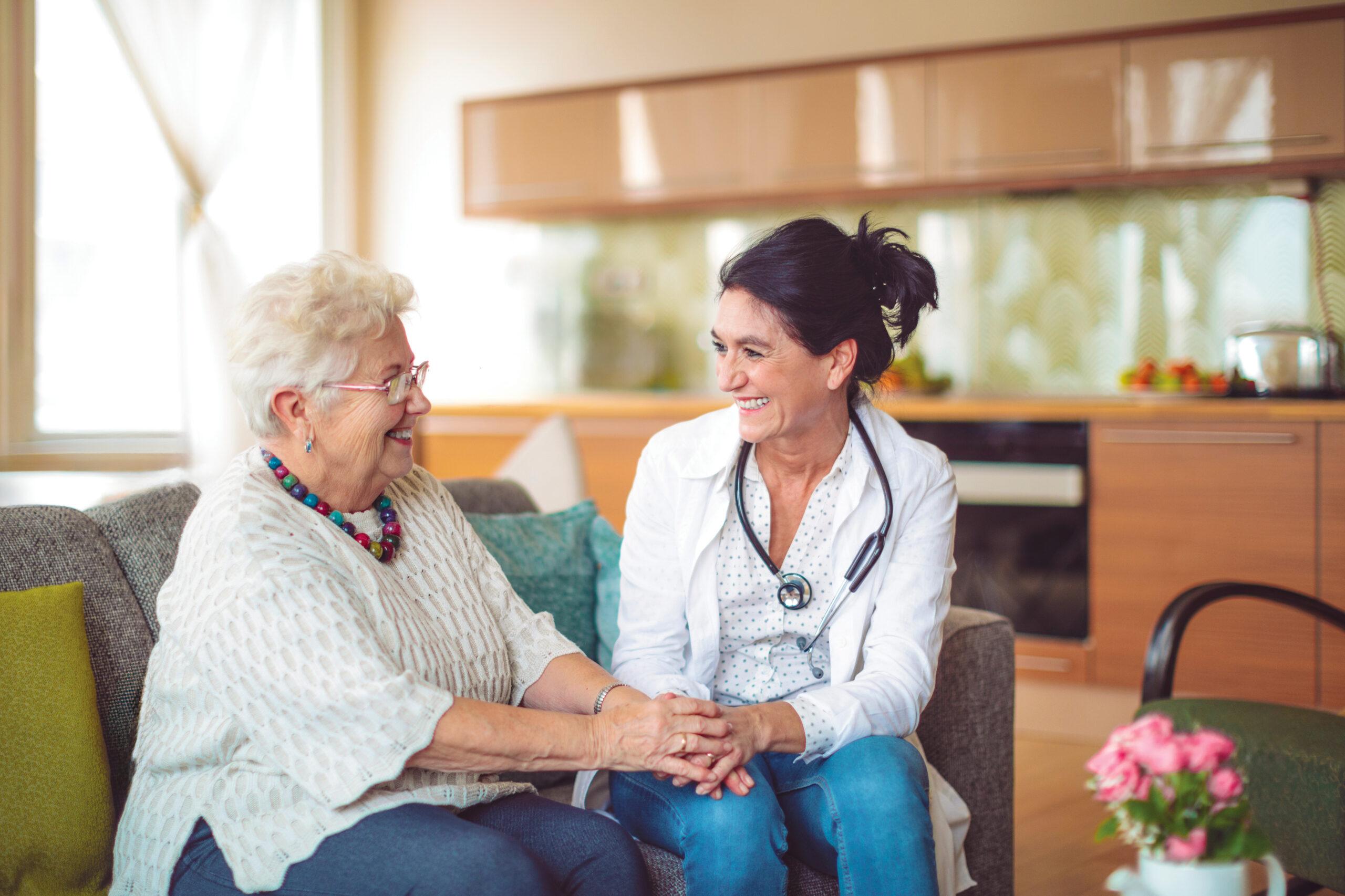 A compassionate nurse holds a senior patient’s hands.