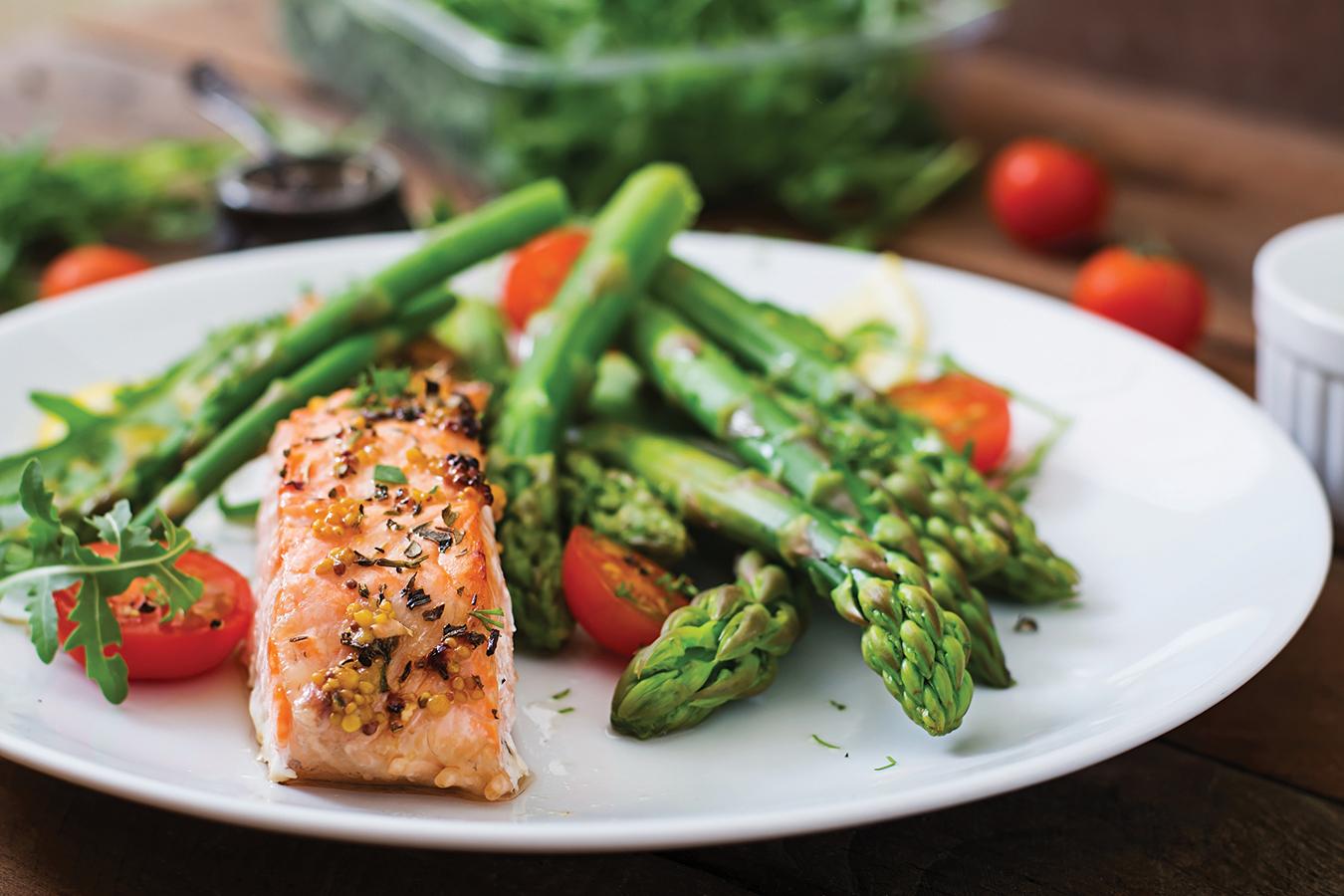 Baked salmon garnished with asparagus and tomatoes with herbs.