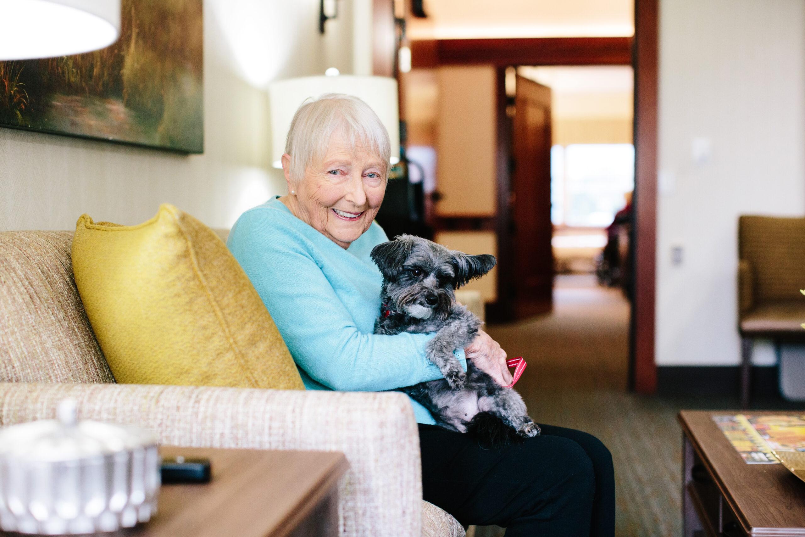 A smiling woman sits with a dog.