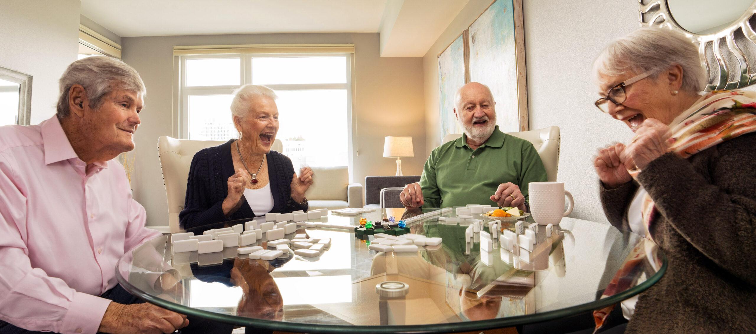 Four friends laugh and smile while playing a tabletop game.
