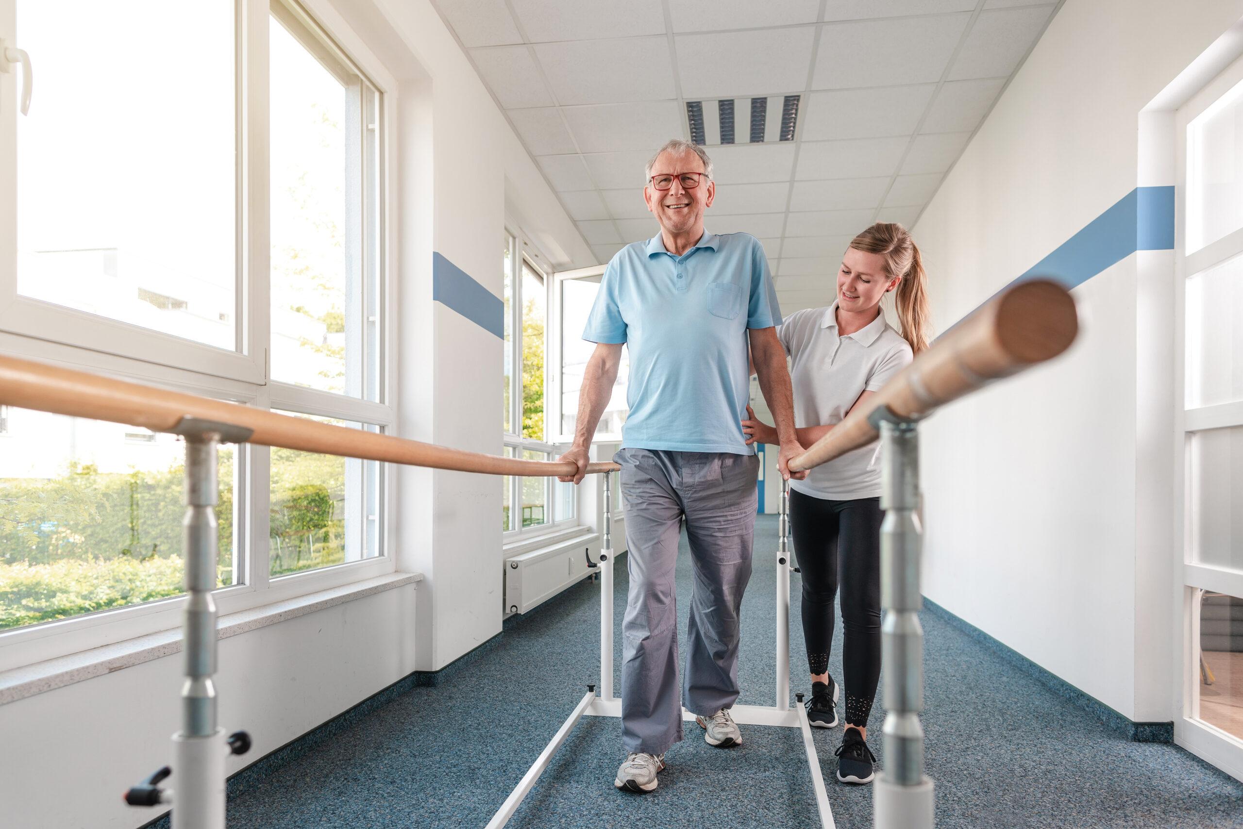 A patient walks down the hallway with the help of a walking device and a physical therapist.